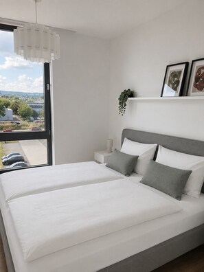 Un dormitorio moderno con una cama grande, una mesita de noche, una planta colgante y cuadros en la pared.