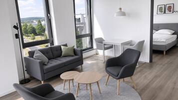 En moderne stue med sofa, to stole, et lille bord og en seng.