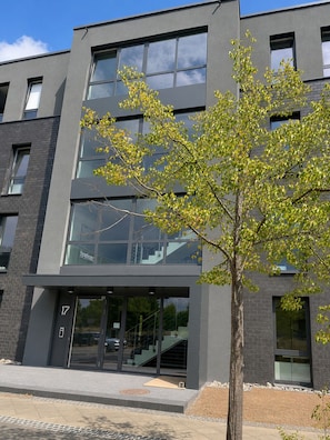 A modern building with large windows and a tree in front.