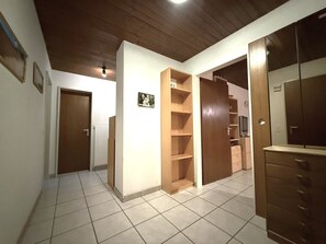 A hallway with a wooden door, a tiled floor, and a wooden wardrobe. - Clabina 32 # 6-bed apartment, Bad, WC 6-Bettwohnung, Bad, WC by Interhome (Leukerbad)