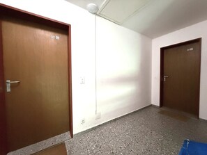 A hallway with two doors, each marked with a number. The floor is covered with speckled tiles. - Clabina 32 # 6-bed apartment, Bad, WC 6-Bettwohnung, Bad, WC by Interhome (Leukerbad)