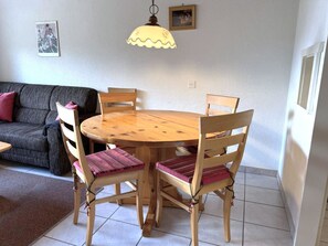 A dining area with a round wooden table, four chairs, and a hanging light fixture. - Clabina 32 # 6-bed apartment, Bad, WC 6-Bettwohnung, Bad, WC by Interhome (Leukerbad)