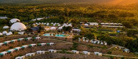 A resort with dome-shaped accommodations, a central pool, and a surrounding landscape with mountains.