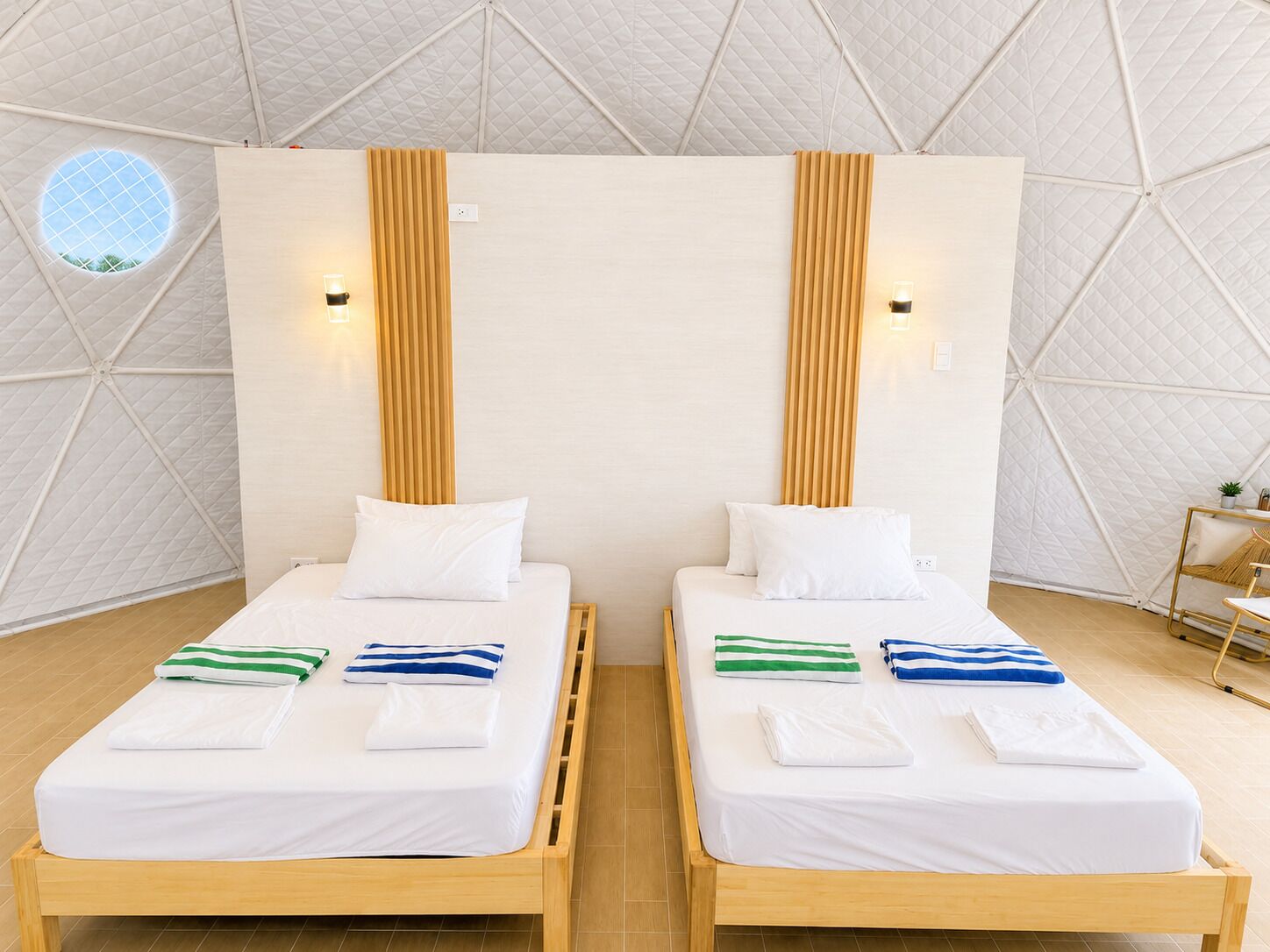 Dos camas individuales con cabeceros de madera, ropa de cama blanca y toallas a rayas.