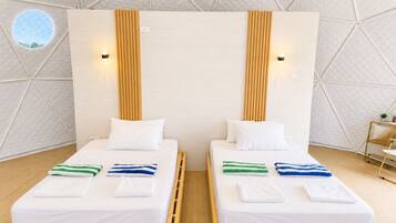 Dos camas individuales con cabeceros de madera, ropa de cama blanca y toallas a rayas.