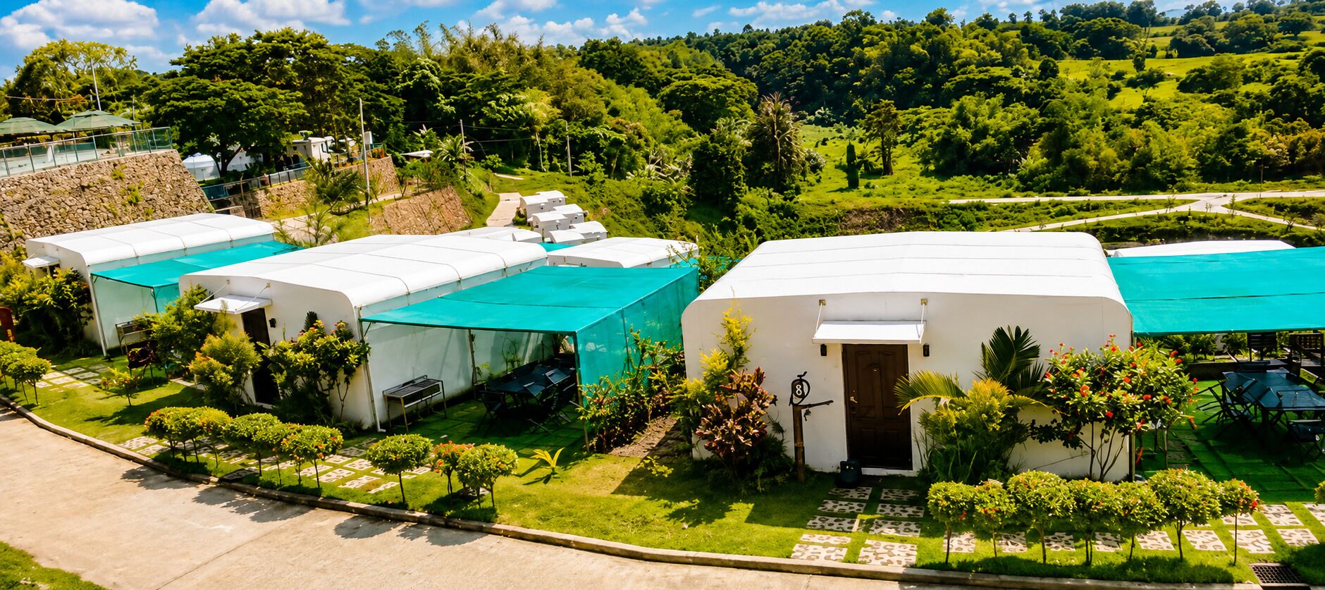 Resort com vários edifícios brancos, piscina e vegetação exuberante.