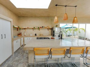 A modern kitchen with a large island, bar stools, pendant lighting, and a view of the outdoors. - Villa Bali - Sosua Mulata II (Sosúa)