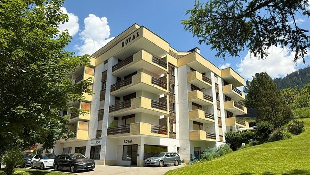 Ein mehrstöckiges Hotel mit Balkonen, einer Auffahrt und einem Parkplatz.