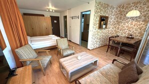 Ein Hotelzimmer mit Bett, zwei Stühlen, einem kleinen Tisch, einer Couch und einem Esstisch.