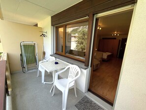 A balcony with a table and chairs, a drying rack, and a view of the interior. - Royal 33 # 2-bed apartment, Dusche, WC 2-Bettwohnung, Dusche, WC by Interhome (Leukerbad)