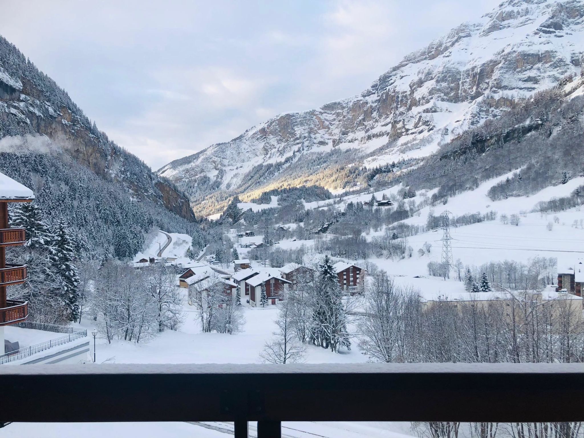 A snow-covered mountain village with wooden buildings and a clear view of the valley.