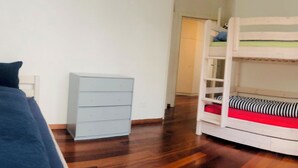 Une chambre avec un lit superposé, une commode et une chaise.