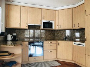 A kitchen with wooden cabinets, a microwave, a dishwasher, and granite countertops. - Edelweiss B 31 # 5-bed apartment, Dusche, WC 5-bed apartment, Dusche, WC by Interhome (Leukerbad)