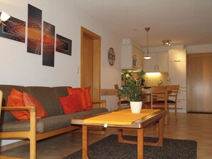 Ein Wohnzimmer mit einer Couch, einem Couchtisch und einem Essbereich mit Stühlen und einer Pflanze.