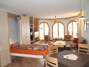 A compact room with a bed, a dining table, and a seating area with chairs. - Château Leukerbad # 2-bed apartment, Dusche, WC by Interhome (Leukerbad)