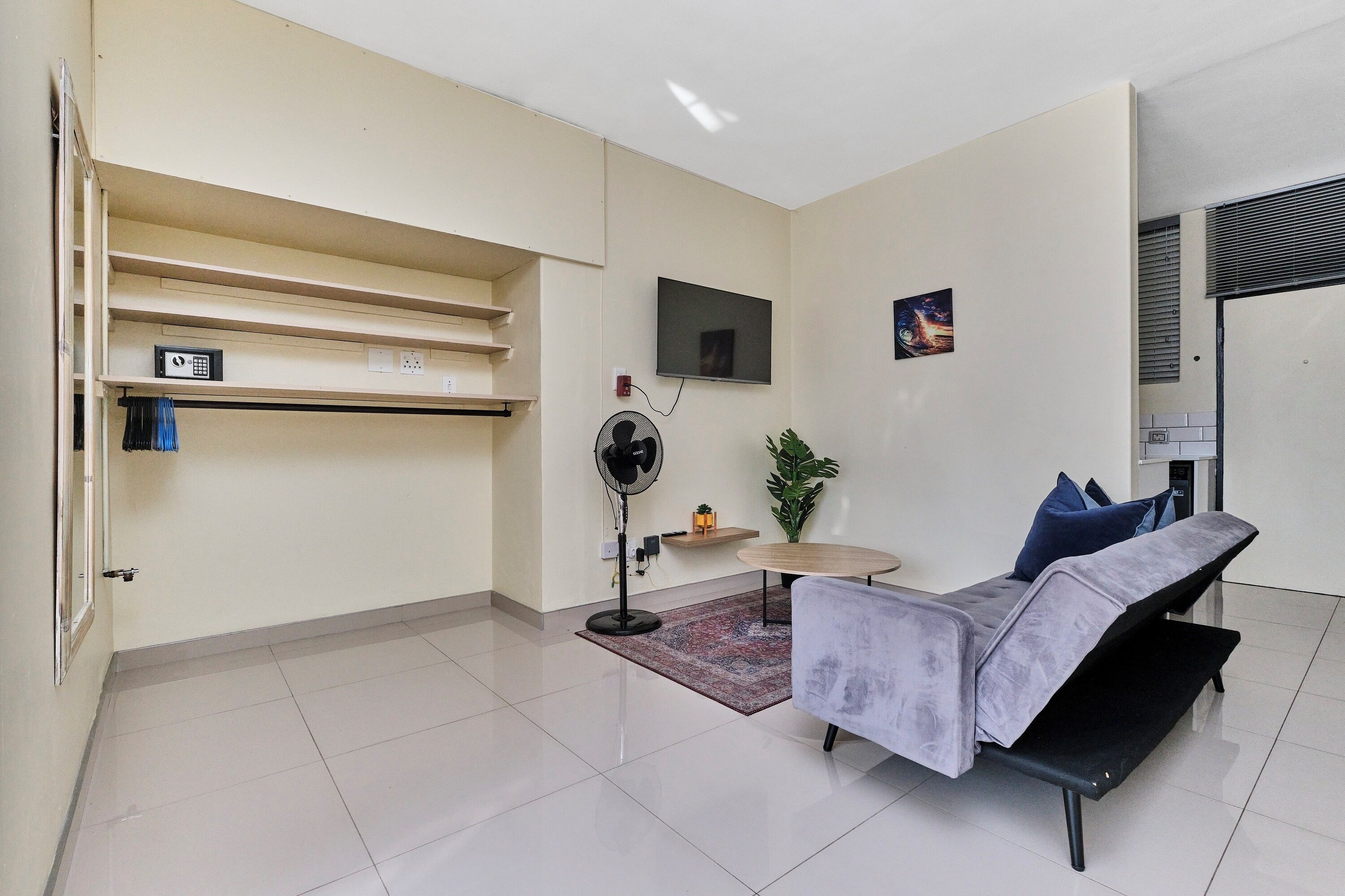 Un salon moderne avec un canapé, un téléviseur à écran plat, un ventilateur et une petite table.