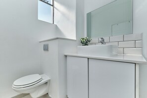 A modern bathroom with a toilet, a sink, and a mirror. - Urban Luxe Studio Illovo Mews by CTHA (Sandton)