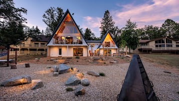 Uma casa moderna de dois andares com um telhado triangular destacado, varanda frontal coberta e entrada de automóveis em cascalho.