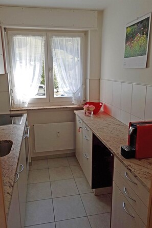 A kitchen with a window, a calendar, and a red appliance. - Gitzifurka 7 # 4-bed apartment, Dusche, WC 4-Bettwohnung, Dusche, WC by Interhome (Leukerbad)