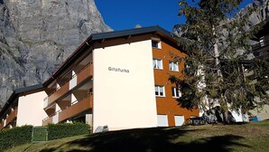 Un edificio de varios pisos con balcones, identificado como 'Gitzifurka', con montañas al fondo.