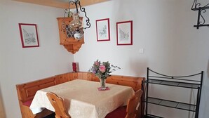 Un comedor con una mesa de madera y bancos, un florero con flores y cuadros en la pared.