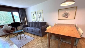 A modern living room with a sofa, a dining table, and a TV. - Royal 41 # 4-bed apartment, Dusche, WC 4-Bettwohnung, Dusche, WC by Interhome (Leukerbad)