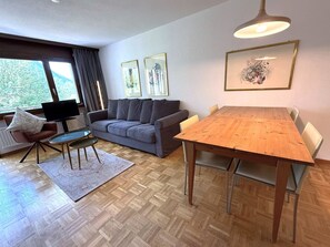 A modern living room with a sofa, a dining table, and a TV. - Royal 41 # 4-bed apartment, Dusche, WC 4-Bettwohnung, Dusche, WC by Interhome (Leukerbad)