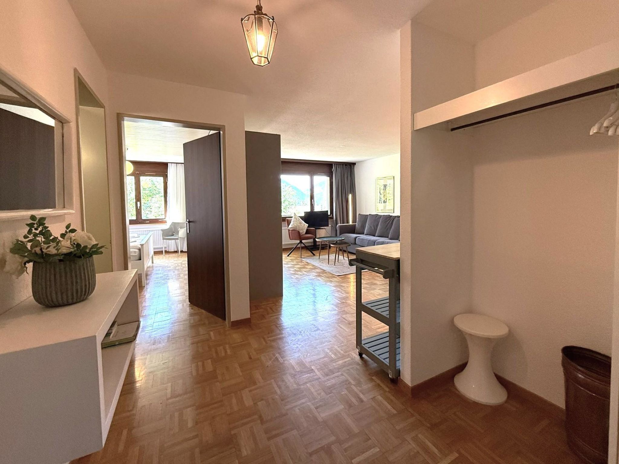 A modern hotel room with a wooden floor, a dining area, and a living space.