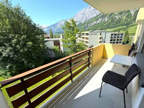 A balcony with a view of mountains, a table, and a chair. - Royal 41 # 4-bed apartment, Dusche, WC 4-Bettwohnung, Dusche, WC by Interhome (Leukerbad)