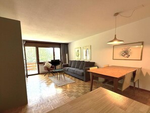 A modern living room with a sofa, a dining table, and a TV. - Royal 41 # 4-bed apartment, Dusche, WC 4-Bettwohnung, Dusche, WC by Interhome (Leukerbad)