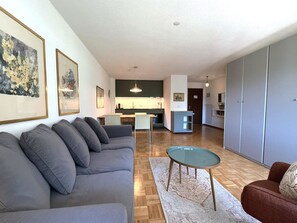 Een moderne woonkamer met een grijze bank, een glazen salontafel en een rode fauteuil.
