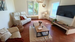 Een woonkamer met een bank, een salontafel, een televisie en uitzicht op de omgeving.