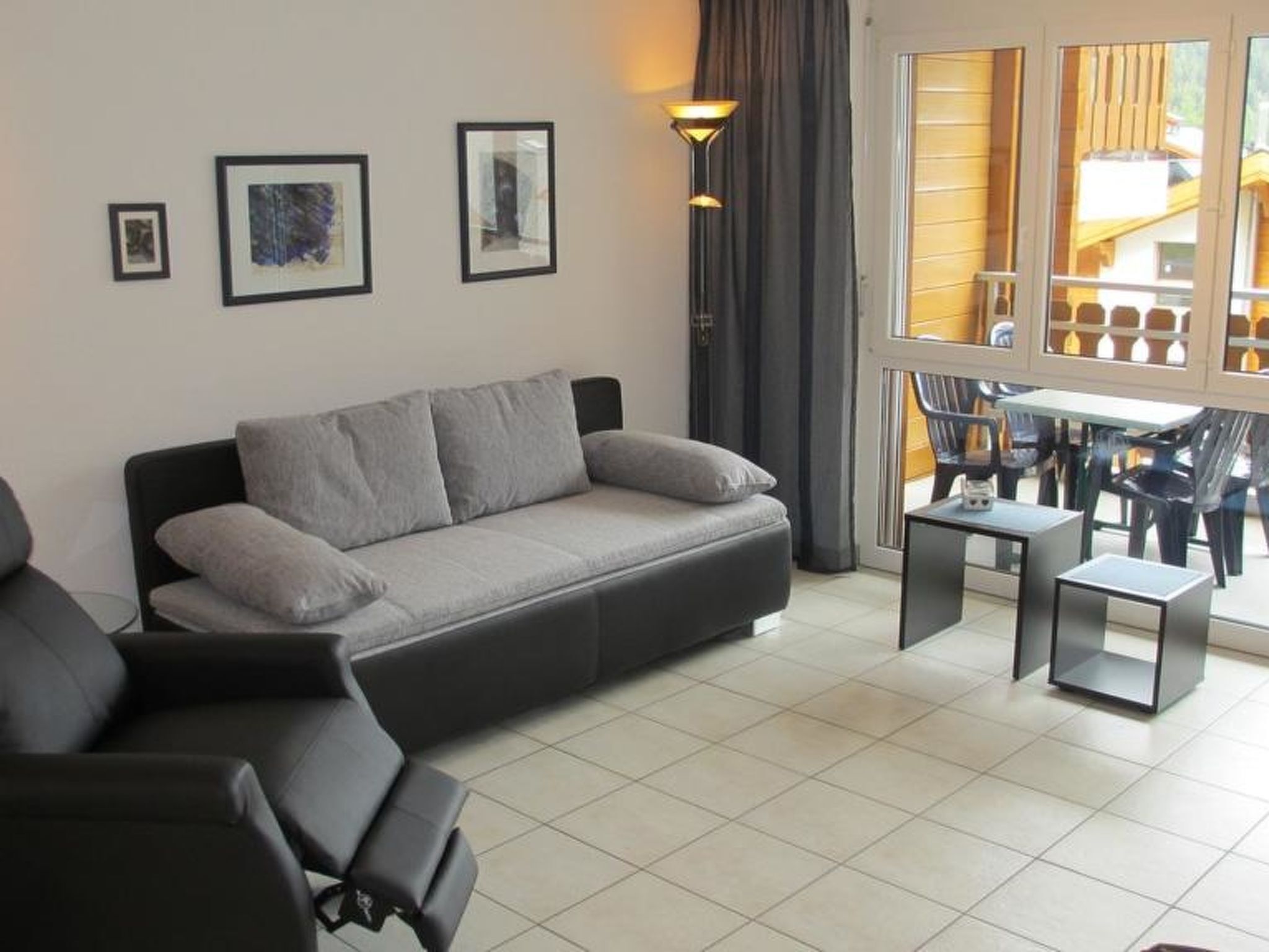 Ein modernes Wohnzimmer mit einer Couch, einem kleinen Tisch und einem Fenster mit Vorhängen.