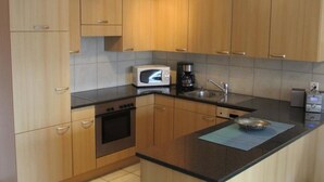 Una cocina con armarios de madera, microondas, cafetera y lavamanos.