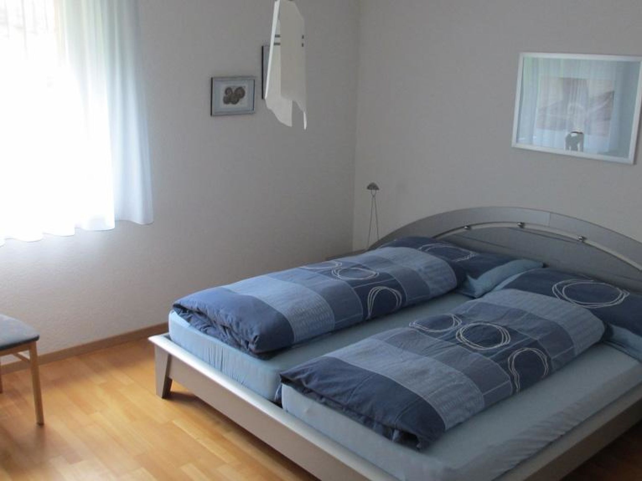 Ein Schlafzimmer mit einem Bett, einem Sessel und einem Fenster mit Vorhängen.