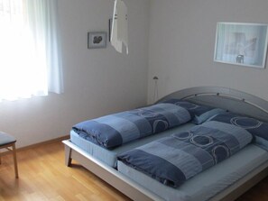 A bedroom with a bed, a chair, and a window with curtains. - Anessa 33 # 4-bed apartment, Bad, WC 4-Bettwohnung, Bad, WC by Interhome (Leukerbad)