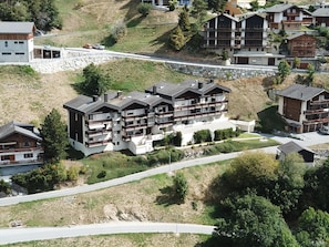 A multi-story building with balconies, situated on a hillside with a road in front. - Albina 40 # 4-bed apartment, Dusche, WC 4-Bettwohnung, Dusche, WC by Interhome (Albinen)