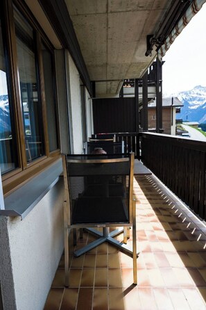 A balcony with a metal table and chairs, a window, and a view of mountains. - Albina 40 # 4-bed apartment, Dusche, WC 4-Bettwohnung, Dusche, WC by Interhome (Albinen)