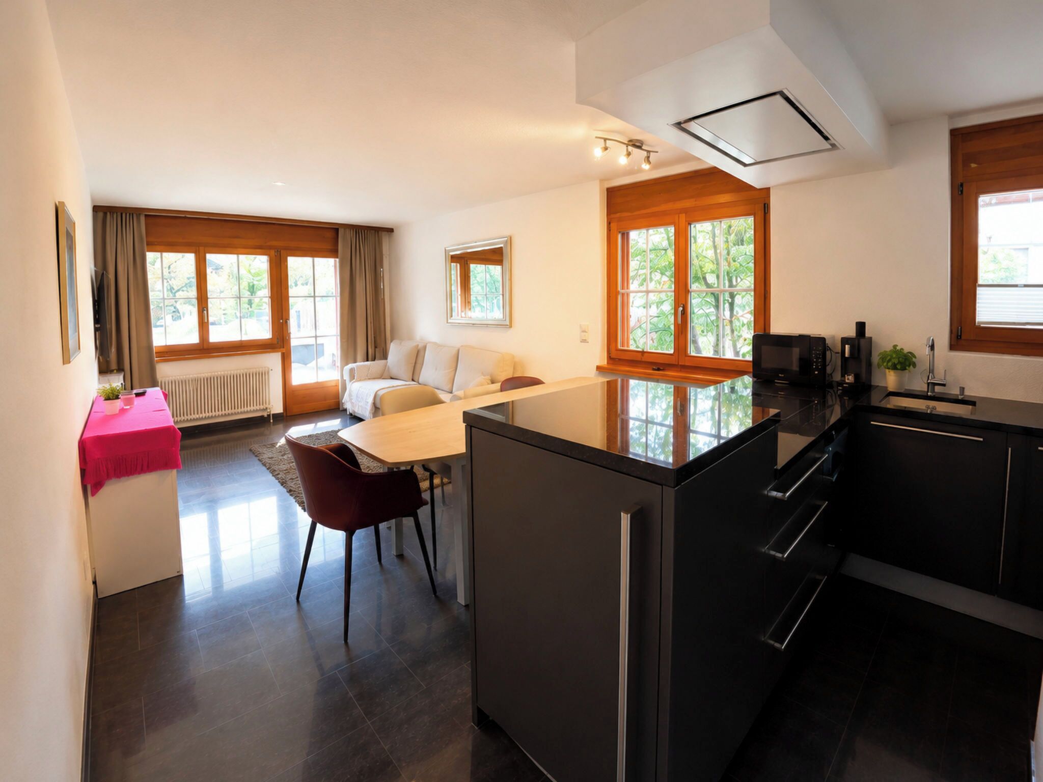 Una cocina moderna con una isla central, un comedor con mesa y sillas, y una sala de estar con sofá.