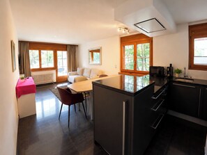 A modern kitchen with a central island, a dining area with a table and chairs, and a living space with a sofa. - Residenz Christina Leukerbad # 5-bed apartment, Dusche, WC by Interhome (Leukerbad)