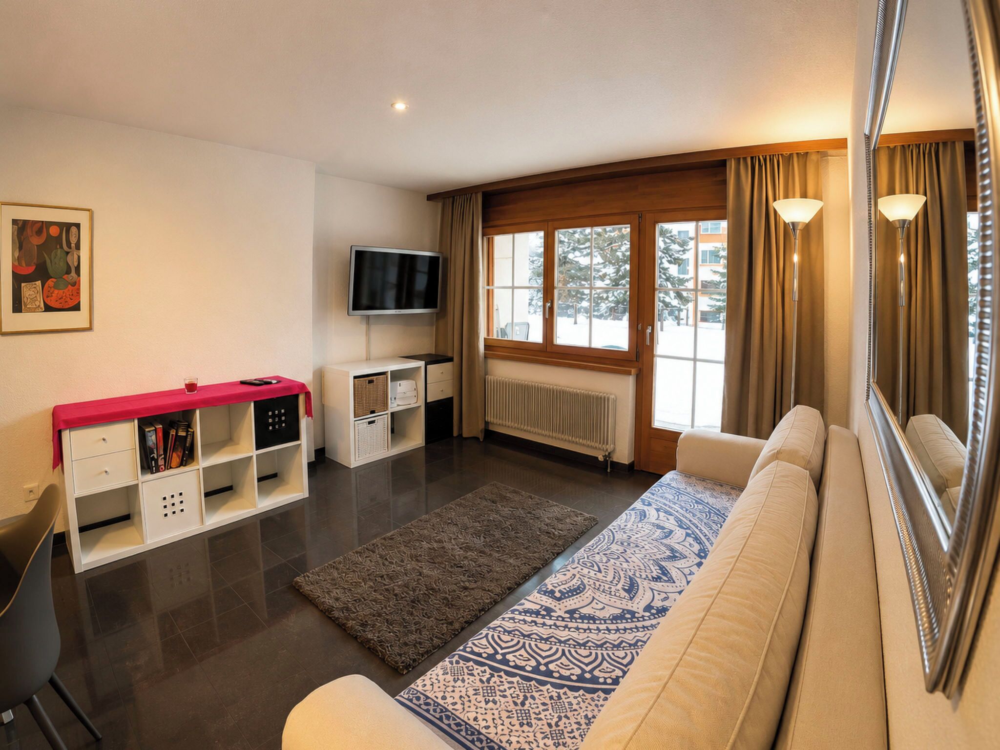 A modern living room with a sofa, a television, a coffee table, and a window with curtains.