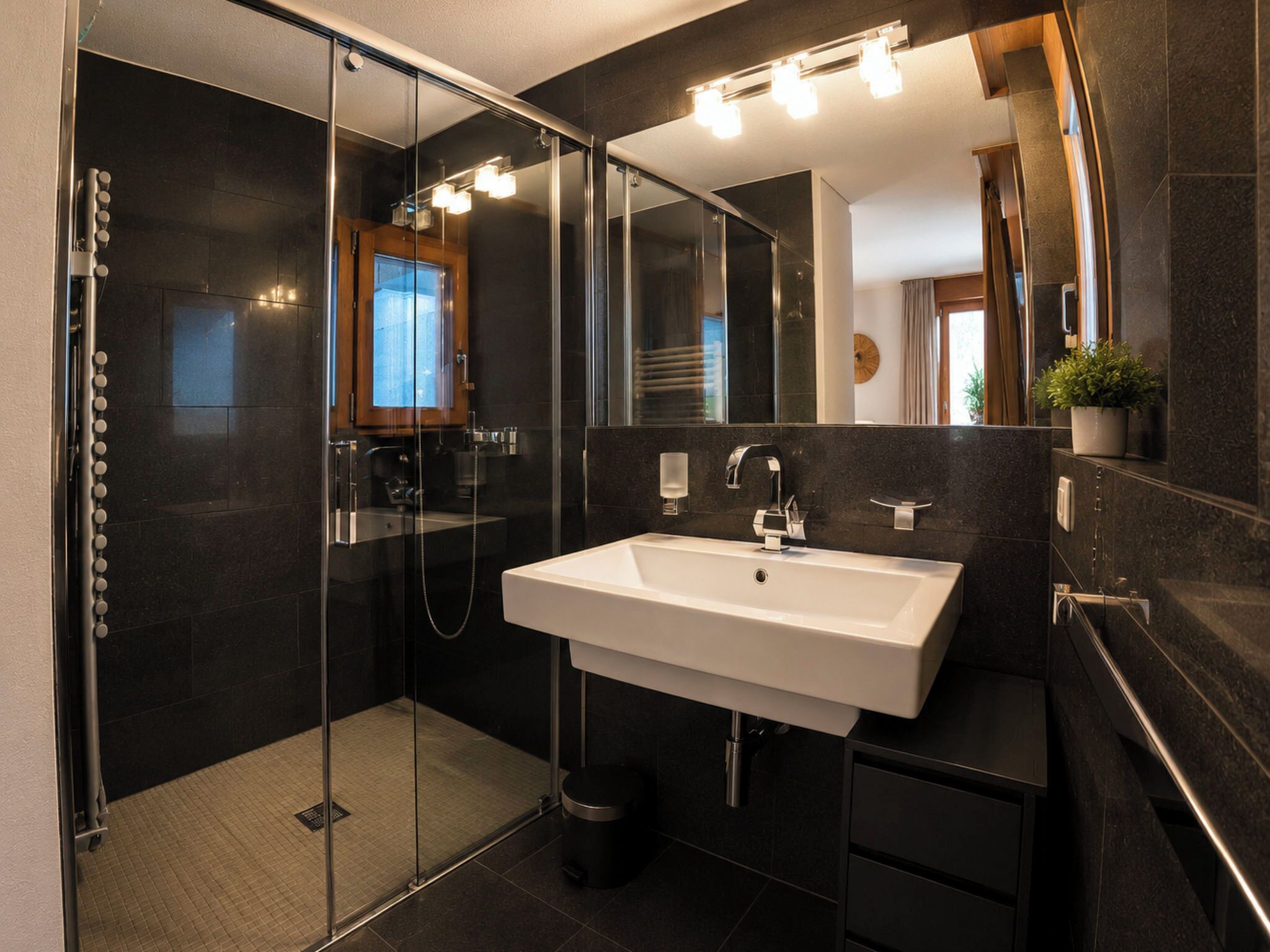 Une salle de bain moderne avec une douche à parois de verre, un lavabo blanc et un grand miroir.