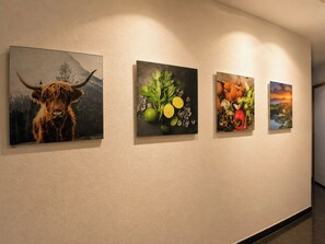 A wall with four framed artworks depicting a bull, fruits, vegetables, and a sunset landscape. - Residenz Christina Leukerbad # 5-bed apartment, Dusche, WC by Interhome (Leukerbad)