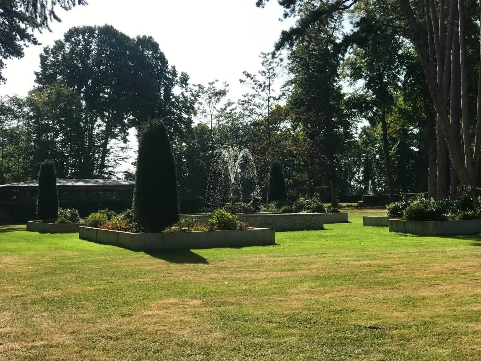 Een verzorgde tuin met strak gemaaid gras en diverse bomen en struiken.