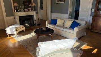 A living room with a sofa, a coffee table, a fireplace, and a mirror.