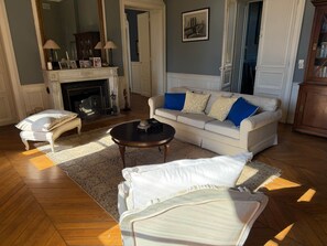 A living room with a sofa, a coffee table, a fireplace, and a mirror. - Katho Stable - KWPN Dressage Horse (Charentonnay)