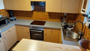 Eine Küche mit Holzausstattung, einem Backofen, einer Spüle und einer Kaffeemaschine.