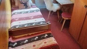 Ein Blockhaus-Interieur mit einem Bett, einem Schreibtisch und einem Stuhl.