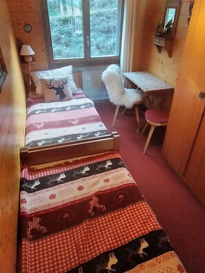 Ein Blockhaus-Interieur mit einem Bett, einem Schreibtisch und einem Stuhl.