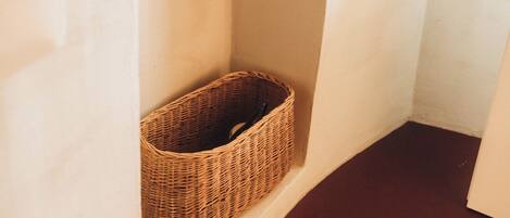 A corner of a room with a wicker basket placed against the wall.